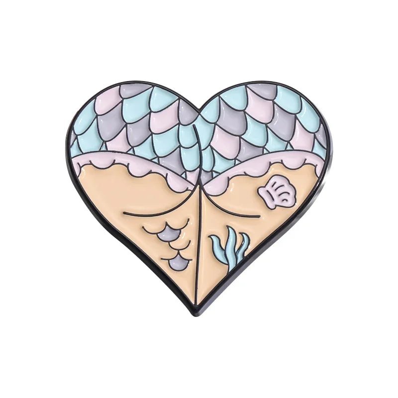 Add mermaid magic to your look with a heart-shaped enamel pin, featuring pastel mermaid scales above a sandy beach scene with waves, a shell, and seaweed.