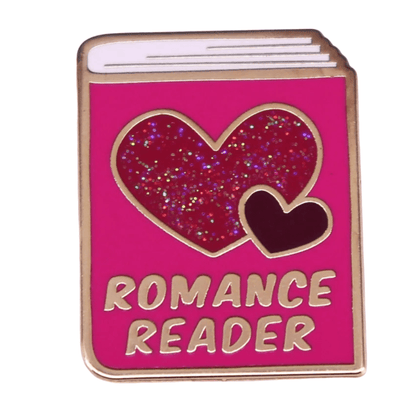Pink enamel pin, shaped like a book with glittery red and dark red hearts and ROMANCE READER in gold at the bottom, is a charming addition to any book lovers badge collection.