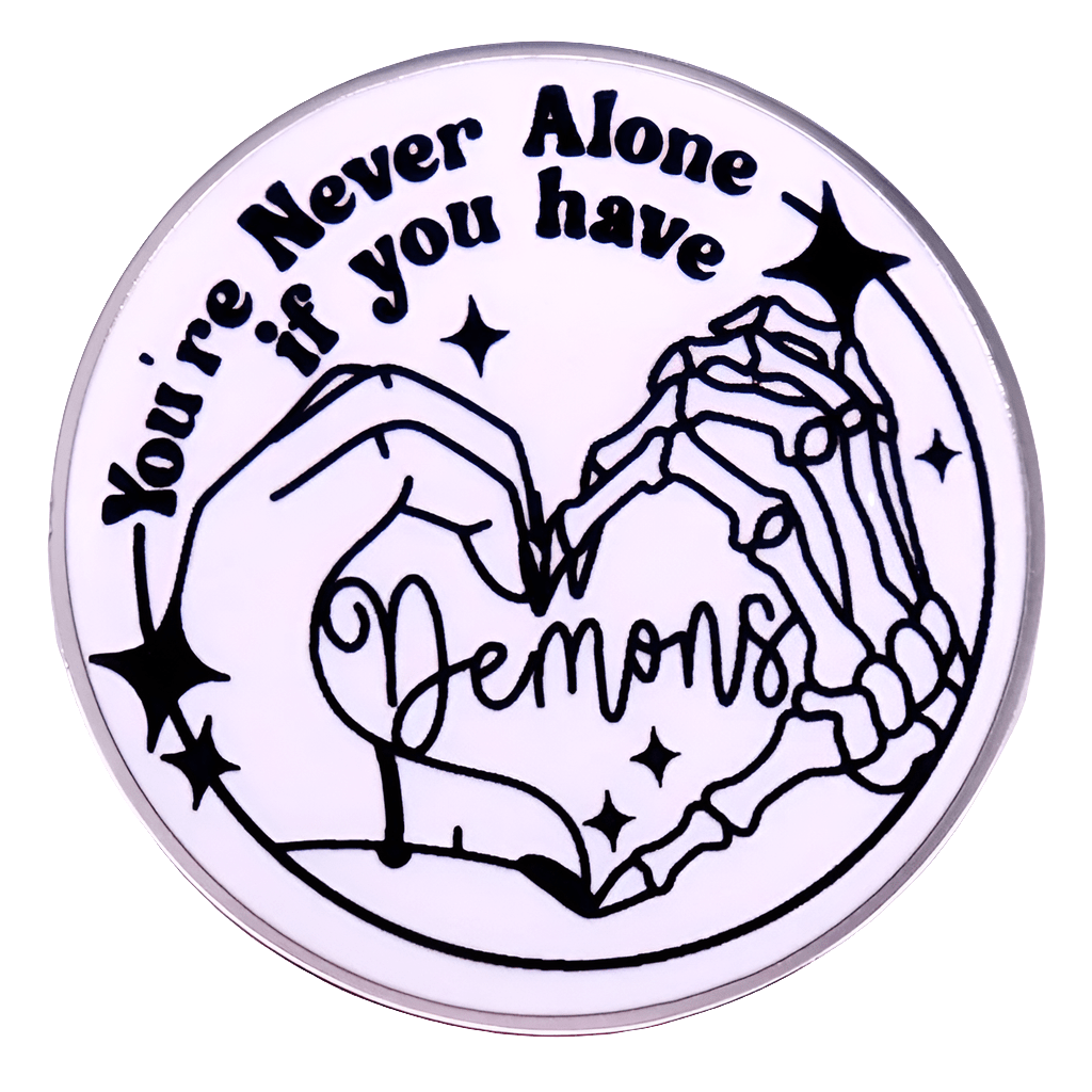A My Cutesy Era round sticker shows a human hand and skeleton hand forming a heart, surrounded by stars. Features the text: You’re never alone if you have demons—a fun match for any love heart enamel pin collection.