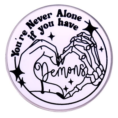 A My Cutesy Era round sticker shows a human hand and skeleton hand forming a heart, surrounded by stars. Features the text: You’re never alone if you have demons—a fun match for any love heart enamel pin collection.