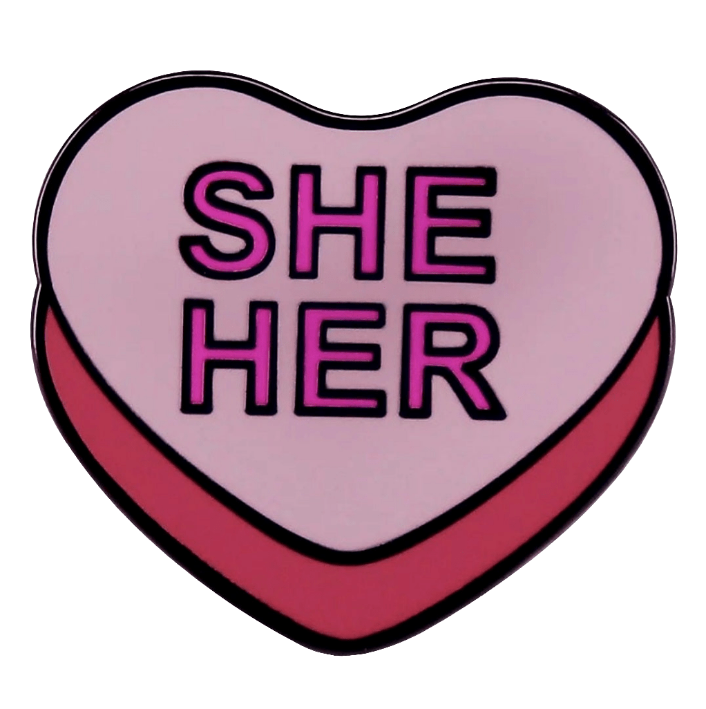 The Kiss Me Later She/Her Pronoun Pin features a pink heart with a light background and bold SHE HER text, making it a stylish way to express your identity.