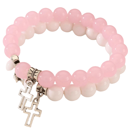 Two Kiss Me Later stretch crystal bead bracelets, featuring round pink and white beads with silver Cross charms, are stacked together for a stylish look against a white background.