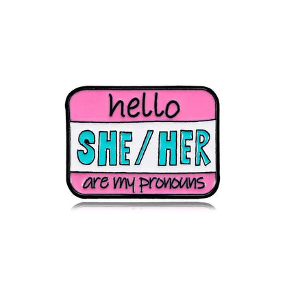 Show off your pronouns with the name tag pin, featuring a pink and white background and hello SHE/HER are my pronouns in black and teal text. Ships worldwide!.