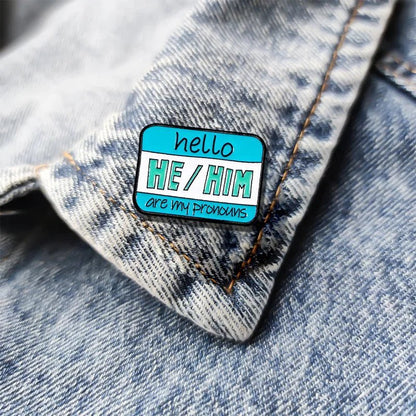 Pronoun pin on a denim jacket reads hello HE/HIM are my pronouns in black and white text on a blue, white, and teal background—ideal for proudly expressing your identity.