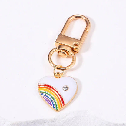 Rainbow gold keychain features a heart-shaped pendant with a rainbow charm and rhinestone—perfect as a pride accessory.