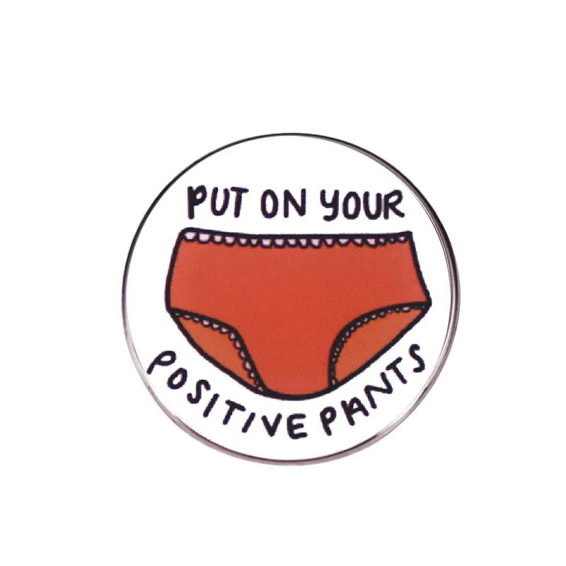 From My Cutesy Era, this playful 1-inch pink enamel pin showcases red underwear and bold black Put on your positive pants text, adding a cheerful accent to any outfit.
