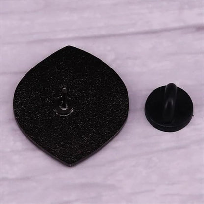 enamel pin with a metal post and black rubber backing rests on a light marbled surface. Order this unique accessory for worldwide shipping.