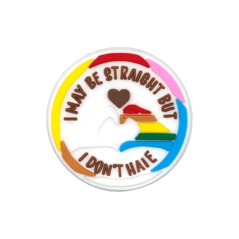 A round pin by Kiss Me Later with I MAY BE STRAIGHT BUT I DONT HATE encircling two hands forming a heart on a Rainbow Flag background—an ideal accessory to celebrate LGBTQ+ pride in your collection.