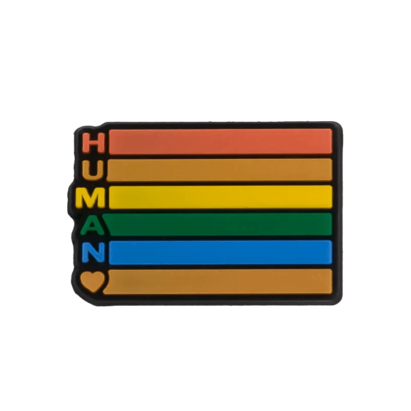 A Kiss Me Later rectangular pin features horizontal red, yellow, green, and blue stripes inspired by the Rainbow Flag. HUMAN is printed vertically on the left with a heart at the bottom—a vibrant pride accessory.