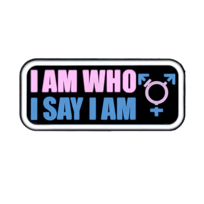 A rectangular Kiss Me Later sign features I AM WHO I SAY I AM in pink and blue beside a transgender symbol in Trans Flag colors—making it a bold accent for your pride charms collection.