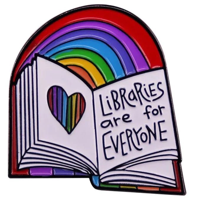 An enamel badge features an open book with a heart-shaped cutout, rainbow colors inside, and “Libraries Are For Everyone” text, topped with a rainbow. Ships worldwide.