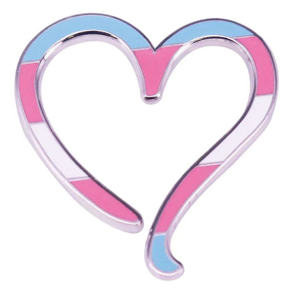 The Kiss Me Later silver heart pin features a heart-shaped enamel badge outlined with stripes in the transgender flag colors—light blue, pink, and white—making it a meaningful accessory.