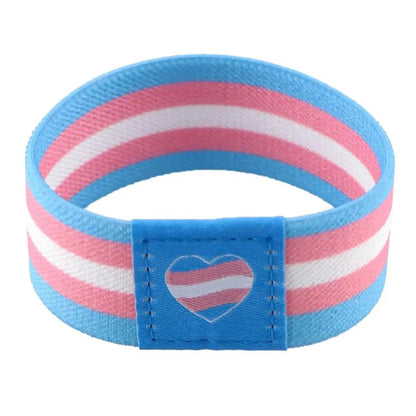 The Gay Skate fabric wristband features blue, pink, and white stripes of the transgender pride flag, plus a small matching heart on a blue patch.