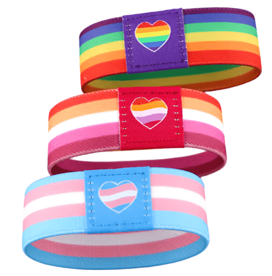 Gay Skate’s set of three fabric wristbands features heart patches with pride flag designs: rainbow on purple, lesbian on red, and transgender on blue—each a vibrant Pride accessory with matching band colors.