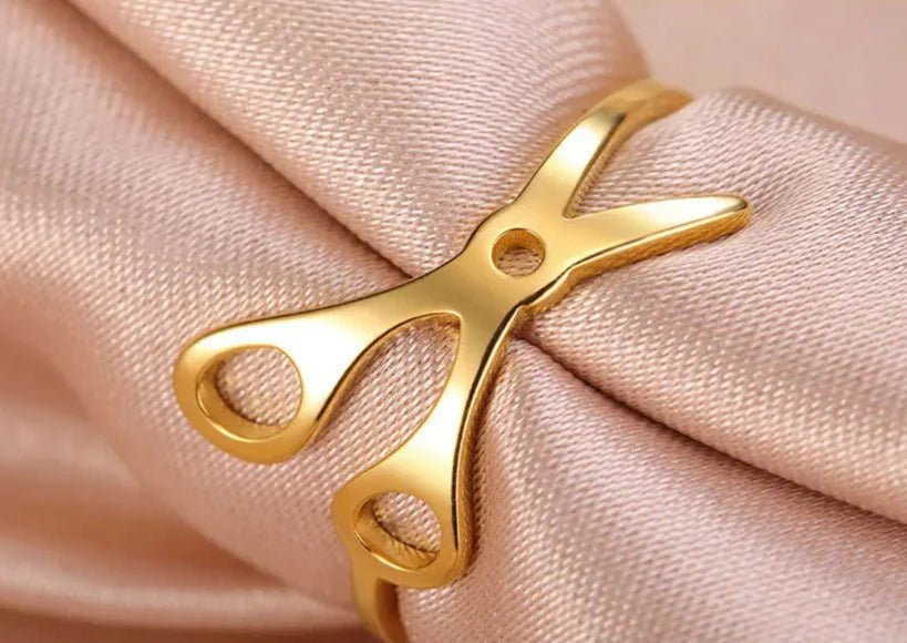Gold Scissor Ring, made of stainless steel and wrapped in light pink satin, showcases a shiny finish and unique design—ideal for anyone seeking standout sapphic pride accessories.