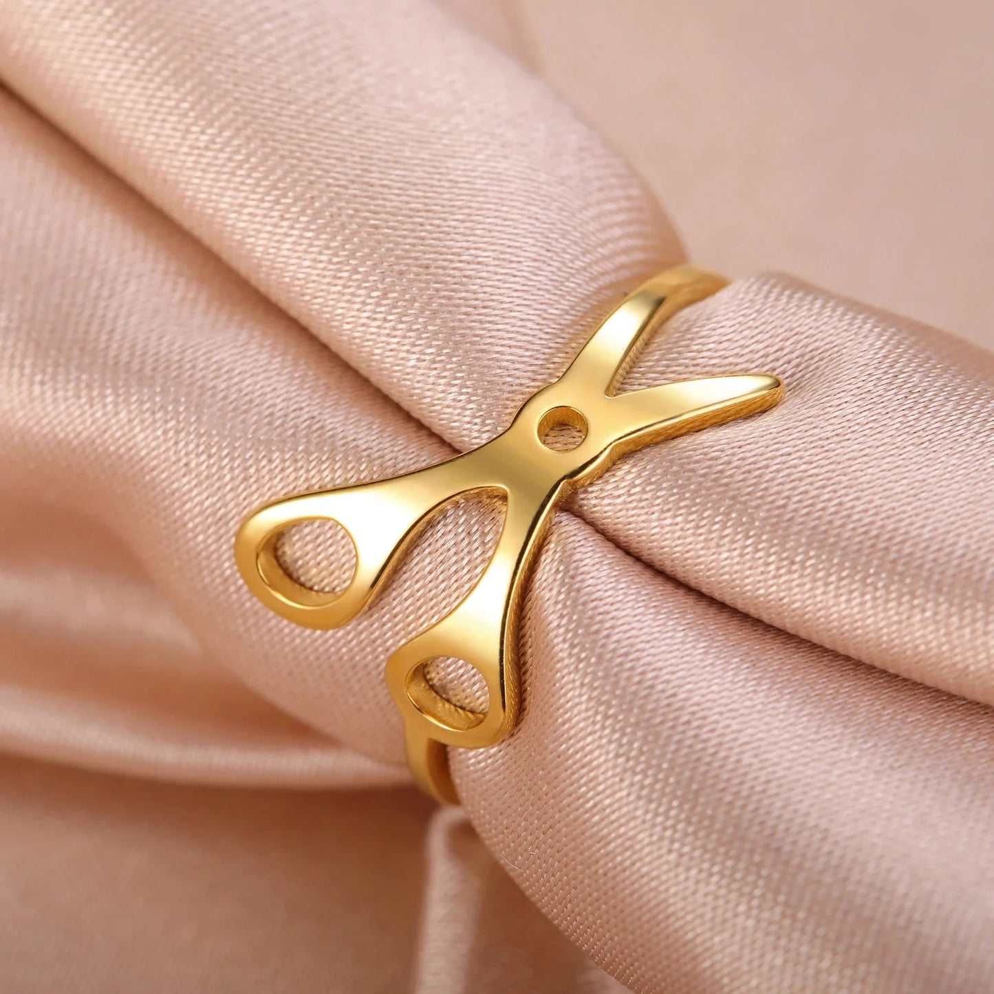 Scissor Ring, crafted in gold and displayed on soft beige satin, is an elegant addition to any collection of sapphic pride accessories.