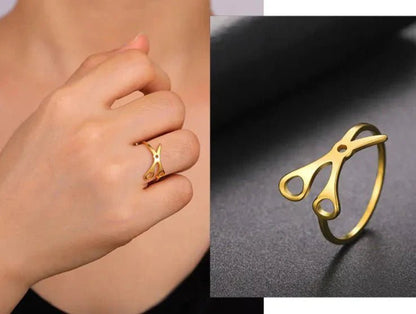 Scissor Ring, crafted from gold-toned stainless steel, is shown on a finger and in close-up on a dark surface—a bold accessory for any sapphic pride collection.