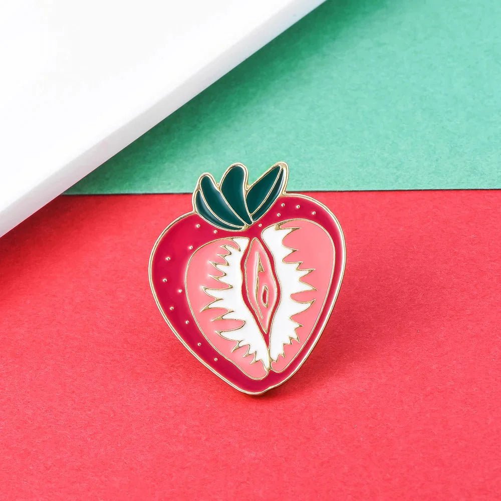 The Kiss Me Later Strawberry Vulva pin features a stylized, abstract vulva on a bold red and green strawberry, ideal for celebrating feminist and body positive vibes. This unique enamel pin makes a playful statement.