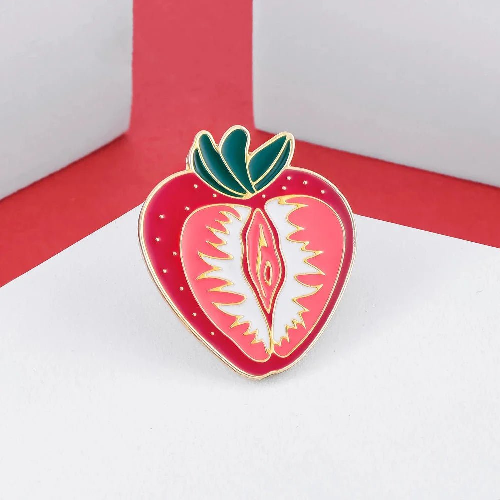 Celebrate sapphic WLW pride with the Strawberry Vulva Pin—a feminist, body-positive accessory shaped like a strawberry and vulva, set on a red and white geometric background.