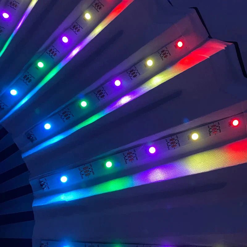 Close-up of folding fan blades with vibrant, multicolored lights from the My Cutesy Era battery powered LED fan, glowing brightly against a dark background.