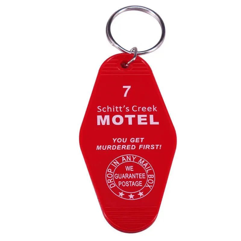 A retro hotel key ring by Kiss Me Later in bold red with white text: 7 Schitts Creek Motel. You get murdered first! Drop in any mailbox—guaranteed postage. Perfect pop culture accessory for fans and collectors.