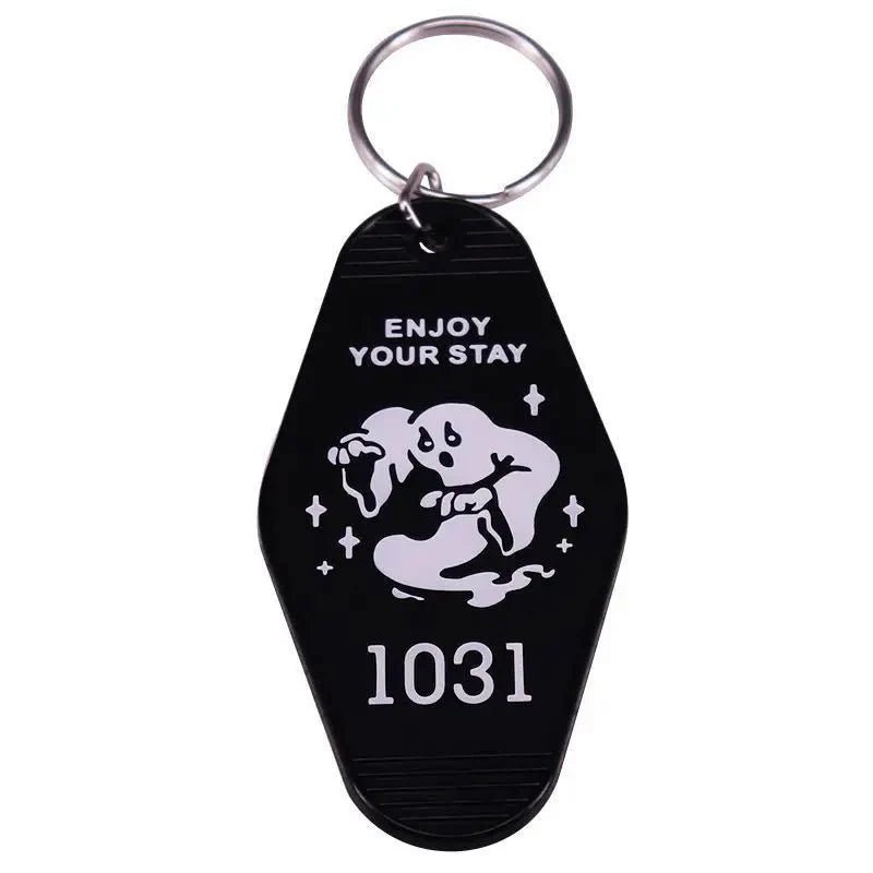 The Kiss Me Later black keychain, inspired by retro hotel key rings, features a white cartoon ghost, ENJOY YOUR STAY above it, and the number 1031 below.