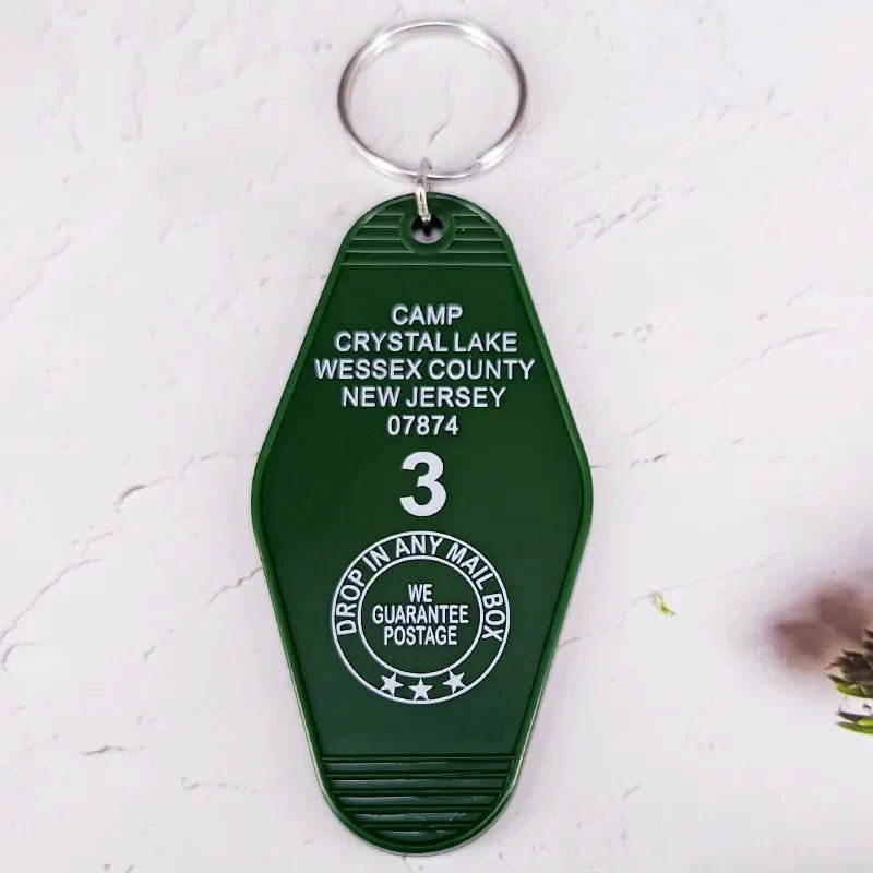 The Kiss Me Later green retro hotel key ring reads: CAMP CRYSTAL LAKE WESSEX COUNTY NEW JERSEY 07874 3. DROP IN ANY MAIL BOX. WE GUARANTEE POSTAGE, all in white capital letters.