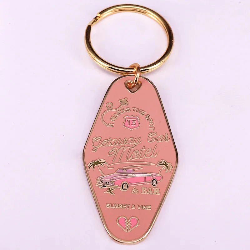 The Kiss Me Later pink retro hotel key ring features gold accents, a classic car, palm trees, and text: Getaway Car Motel & Bar, Sunset & Vine, Parking in the Back. Includes a gold key ring.