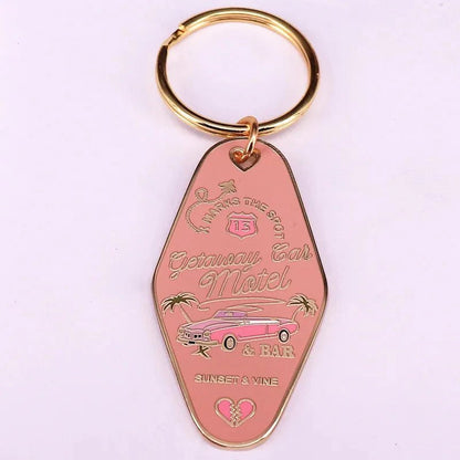 The Kiss Me Later pink retro hotel key ring features gold accents, a classic car, palm trees, and text: Getaway Car Motel & Bar, Sunset & Vine, Parking in the Back. Includes a gold key ring.