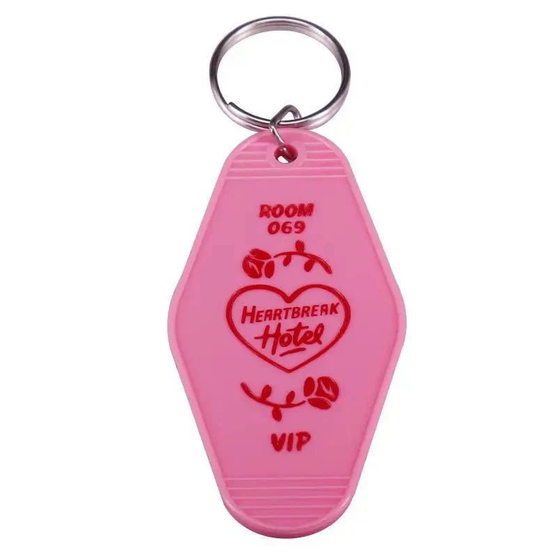 A pink, retro-style hotel keychain by Kiss Me Later with a metal ring. Labeled ROOM 069, HEARTBREAK Hotel inside a heart with roses, and red VIP text—perfect for fans of colorful pop culture key rings.