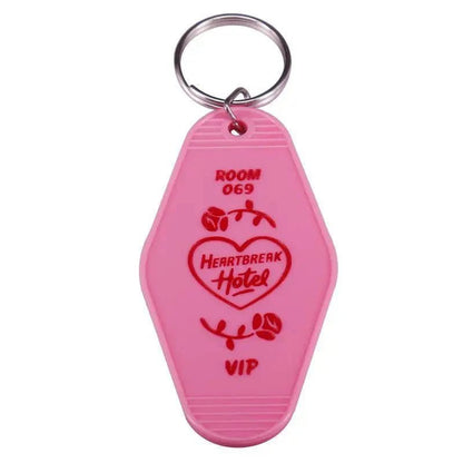 A pink, retro-style hotel keychain by Kiss Me Later with a metal ring. Labeled ROOM 069, HEARTBREAK Hotel inside a heart with roses, and red VIP text—perfect for fans of colorful pop culture key rings.