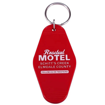Red retro hotel key ring by Kiss Me Later, labeled Rosebud Motel, Schitt’s Creek, Elmdale County with a silver ring and “Follow us on Tweeters!”—a fun gift for pop culture fans and lovers of colorful accessories.
