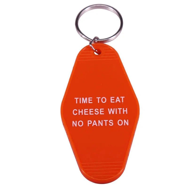 An orange retro hotel key ring by Kiss Me Later features white text: TIME TO EAT CHEESE WITH NO PANTS ON—a playful, pop culture-inspired addition to your colorful key ring collection.