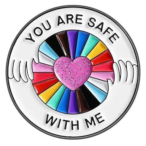 Show your pride with a circular rainbow pin: “You are safe with me.” Two hands hold a colorful wheel and pink glitter heart. Celebrate love and inclusion—worldwide shipping available.