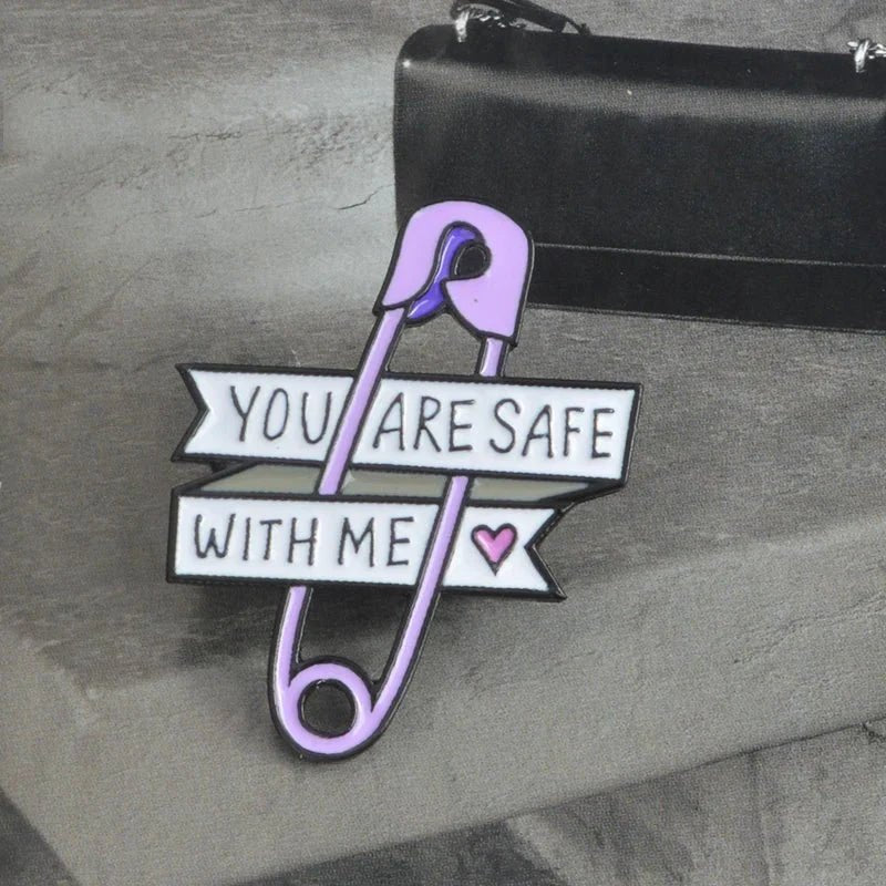 The Gay Skate purple safety pin enamel badge features You are safe with me banners and a pink heart on a grayscale background—a thoughtful addition to your pride collection.