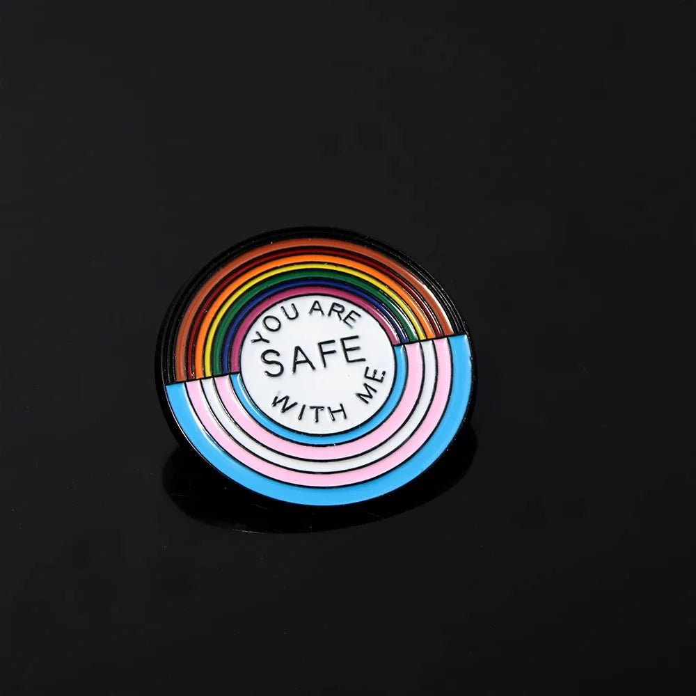 Circular enamel pin features rainbow and pastel stripes with YOU ARE SAFE WITH ME on a black background. Ideal for rainbow pride enamel badge collectors. Worldwide shipping available!.