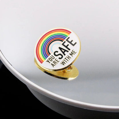 A round pin with a rainbow and “You are safe with me” in bold, shown on a reflective surface—perfect with pride badges. Enjoy worldwide shipping on all items.