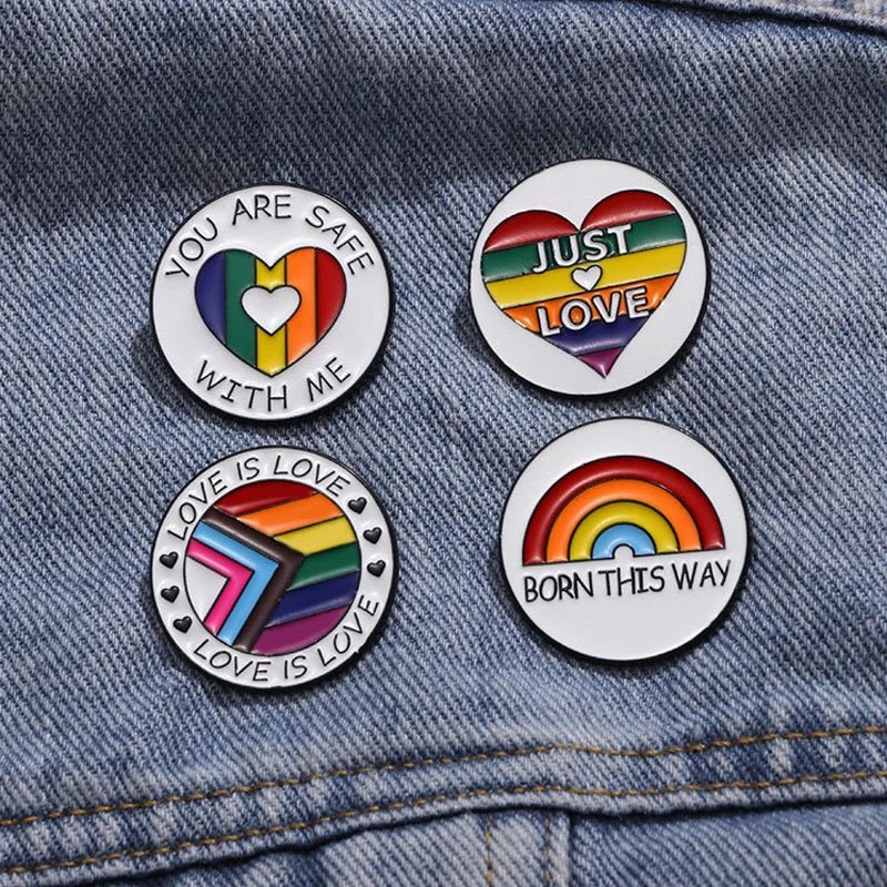 Show your pride with four colorful rainbow pride enamel pins—YOU ARE SAFE WITH ME, JUST LOVE, LOVE IS LOVE, and BORN THIS WAY—pinned to blue denim. Enjoy worldwide shipping!.