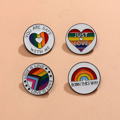 Four round rainbow pride enamel pins with LGBTQ+ designs—each featuring affirming messages like You are safe with me, Just Love, love is love, and Born this way. Worldwide shipping available.